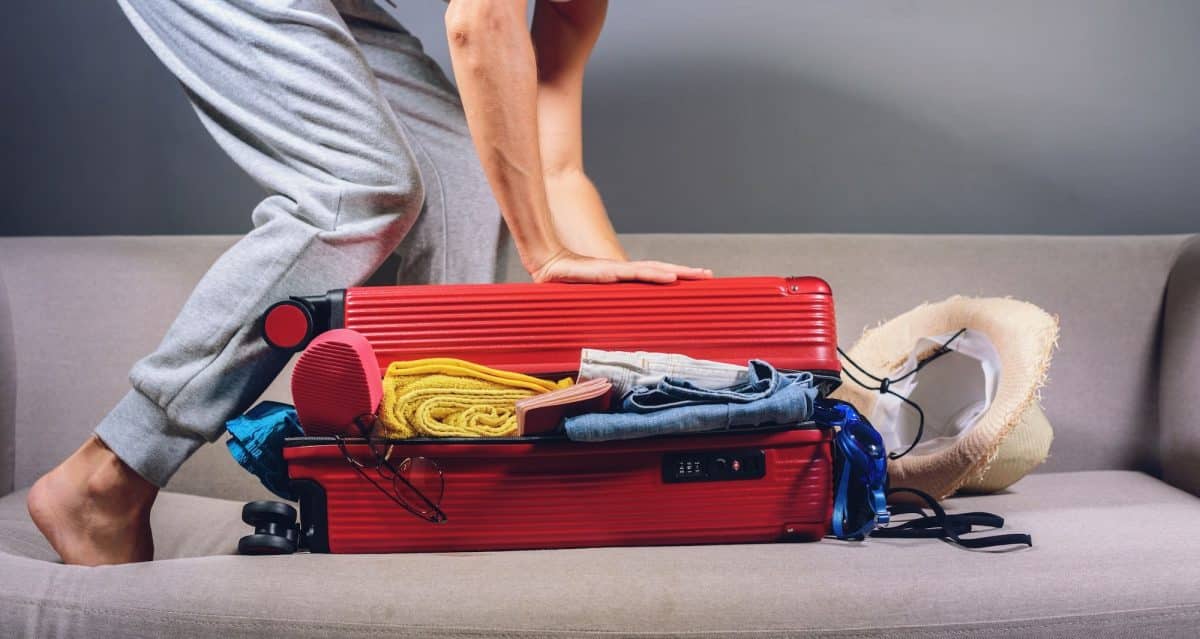 Femme préparant une valise rouge pour un voyage aventureux